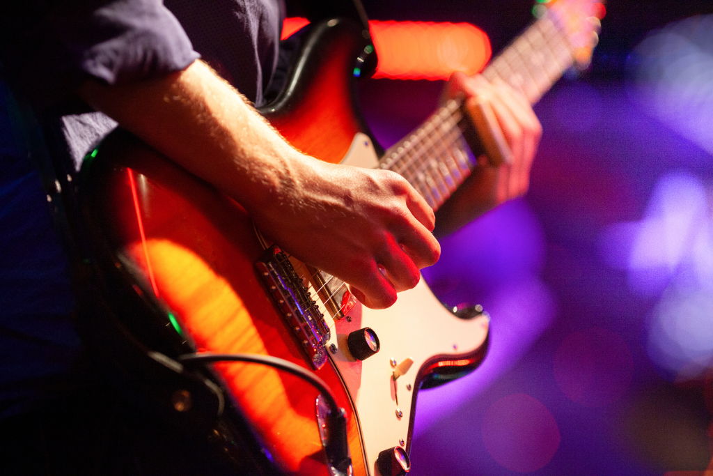 imagem de um guitarrista sgurando uma guitarra, so da pra ver as maos dele