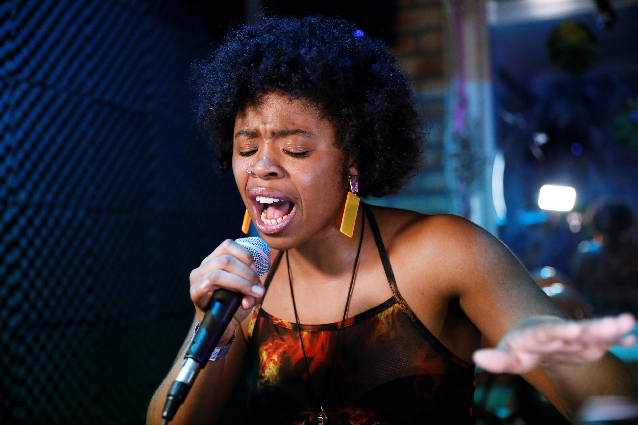 moça jovem e negra segurando um microfone cantando